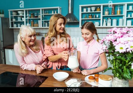 Image Cinematic d'une femme âgée et de sa fille et petite-fille qui cuisinait et préparait de la nourriture dans sa belle cuisine. Grand-mère préparant des gâteaux an Banque D'Images