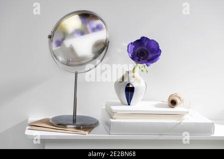 Une anémone bleue dans un vase multicolore dans le style des années 70 sur la table avec des livres comme décoration intérieure. Banque D'Images