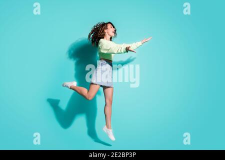 Pleine longueur taille de corps profil de côté photo de fille allant embrassez les prises sautent isolées sur un fond bleu sarcelle éclatant avec espace de copie Banque D'Images