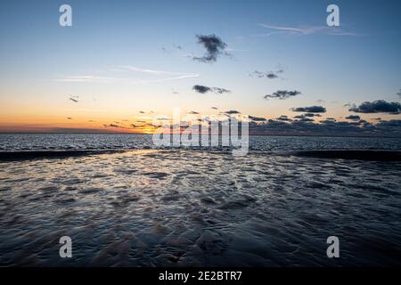 Vue sur le soleil couchant qui brille sur la mer et se reflète sur la plage, nuages avec des bords ensoleillés. Paysage. Photo de haute qualité montrant le concept de liberté et de rêves Banque D'Images