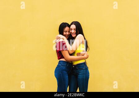 De jeunes amis latino-américains embrassant contre un mur jaune à l'extérieur - concept d'amour et d'amitié Banque D'Images