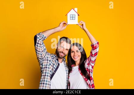 Photo portrait de la petite famille tenant le modèle de la tête isolé sur un arrière-plan jaune vif Banque D'Images