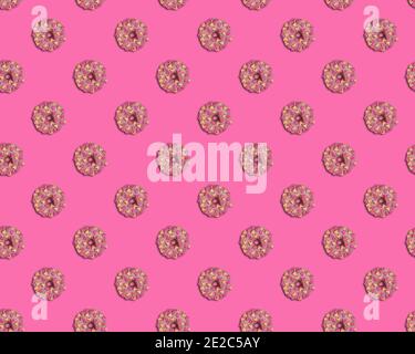 Motif sans couture avec de beaux beignets émaillés de chocolat rose et de coeurs guimauves de couleur rose et pêche sur fond rose. Vue depuis Banque D'Images