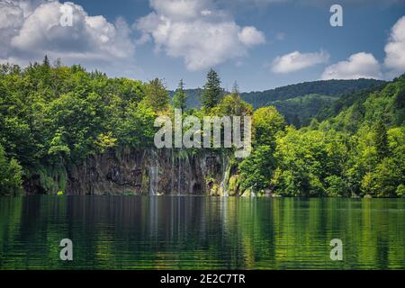 Belles cascades illuminées par la lumière du soleil et reflétées dans le lac. Forêt verdoyante, Parc national des lacs de Plitvice Patrimoine mondial de l'UNESCO en Croatie Banque D'Images