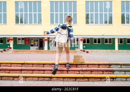 Portrait de l'enfant avec sac à dos bondissant . le garçon court un sac à dos autour de la cour d'école.enfance, concept d'apprentissage de l'éducation Banque D'Images