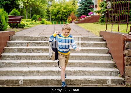 Portrait enfant scolaire avec sac à dos bondissant . le garçon court un sac à dos autour de la cour d'école.enfance, éducation apprentissage concept Banque D'Images