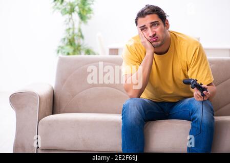 Jeune homme jouant à des jeux de joystick à la maison Banque D'Images