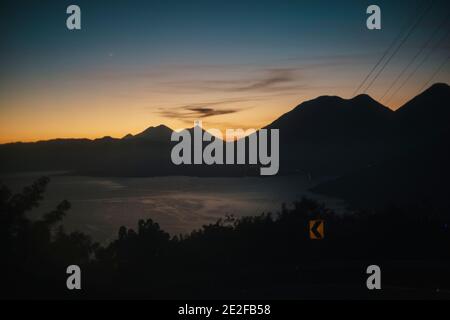 Lever du soleil sur le lac Atitlan avec un ciel dégradé et coloré au-dessus de la montagne Pics et volcans - paysage de lac entouré par des volcans dedans Guatemala Banque D'Images