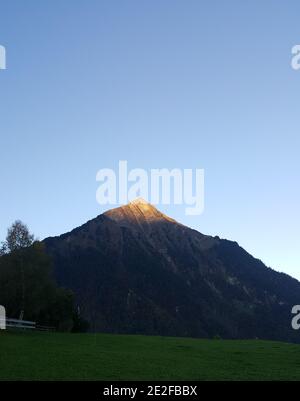 Photo verticale d'une montagne touchée par la lumière du soleil sous la lumière du soleil ciel bleu Banque D'Images