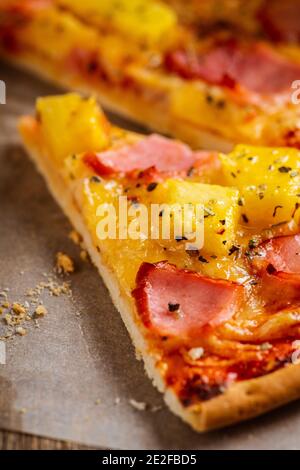 Pizza hawaïenne fraîchement cuite avec ananas et jambon fraîchement hachés sur fond de bois rustique. Mise au point sélective. Banque D'Images