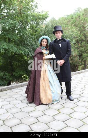 Homme et femme en costumes du XIXe siècle marcher dans le stationnement Banque D'Images