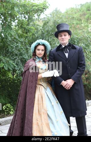 Homme et femme en costumes du XIXe siècle marcher dans le stationnement Banque D'Images