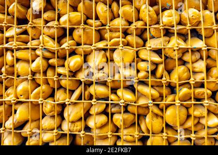 Gros plan sur les pierres rondes orange de la grille. Les grosses pierres sont recouvertes d'un fond métallique en maille. Clôtures en matériaux naturels pour l'environnement. Orange Banque D'Images