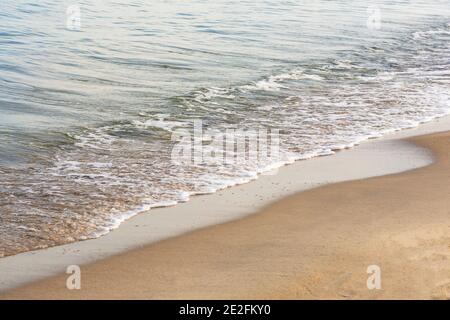 Vague douce avec de la mousse blanche sur le sable ou l'océan. Mise au point sélective, vue brouillard. Banque D'Images