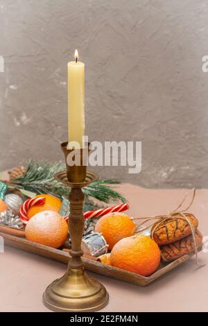 Bougie de Noël avec flamme dans un chandelier vintage. Table du nouvel an avec mandarines dans la neige. Mise au point sélective, arrière-plan flou. Banque D'Images