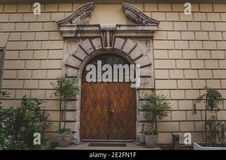 porte en bois à deux feuilles sous une arche semi-circulaire de pierre, avec des pots avec des buissons Banque D'Images