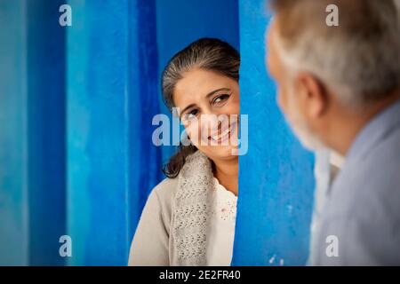 UNE FEMME ADULTE HEUREUSE REGARDANT AVEC AMOUR SON MARI EN SE TENANT DEBOUT DERRIÈRE UN MUR Banque D'Images