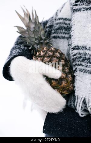 Une fille en moufles tient l'ananas en hiver Banque D'Images