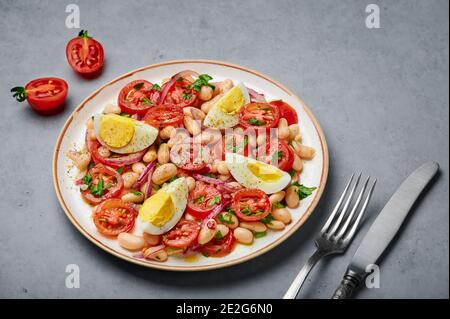 Une salade Piyaz sur une assiette blanche sur une table en béton gris. Cuisine turque plat végétarien. Cuisine du Moyen-Orient. Banque D'Images