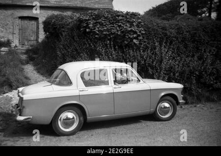 Années 1950, historique, sur une voie rurale, un petit garçon assis dans le siège conducteur d'une voiture familiale, un Hillman Minx, Waving, Angleterre, Royaume-Uni. Fondée en 1907, la société de voitures Hillman était basée près de Coventry et le Hillman Minx était en production de 1931 à 1970, avec de nombreuses versions différentes. La voiture vue ici est peut-être la série Minx V. Hillman, à l'origine un fabricant de vélos, a été repris par les frères Rootes en 1928. Banque D'Images