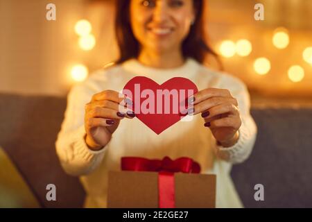 Femme souriante petite amie montrant le cœur rouge à son petit ami pendant rencontres en ligne Banque D'Images