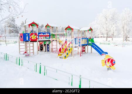 Région de Moscou, Kolomna, Russie-18 décembre 2018: Aire de jeu pour enfants avec maisons en bois rouge-bleu-jaune et toboggans avec neige blanche parmi les tr Banque D'Images