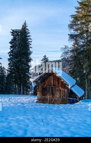 grange de foin enneigée avec des glaçons sur le toit. Hiver, schräger Stadel in der Schneelandschaft mit Eiszapfen am Dach. Champ de neige au soleil du soir Banque D'Images