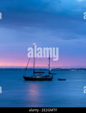 Yacht au large de la côte nord du Kent à Whitstable au crépuscule. Banque D'Images