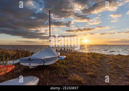 Bateaux sur la plage de Whitstable sur la côte nord du Kent au coucher du soleil. Banque D'Images