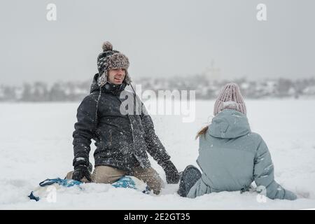 Homme avec petite amie tombant dans le tube de neige. Jeune couple heureux marchant en hiver Banque D'Images