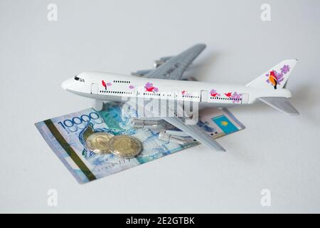 Avion jet avec kazakhstan monnaie nationale kzt tenge sur le arrière-plan blanc Banque D'Images