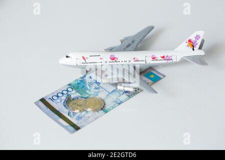 Avion jet avec kazakhstan monnaie nationale kzt tenge sur le arrière-plan blanc Banque D'Images