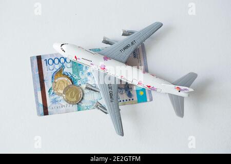 Avion jet avec kazakhstan monnaie nationale kzt tenge sur le arrière-plan blanc Banque D'Images