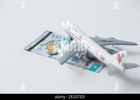 Avion jet avec kazakhstan monnaie nationale kzt tenge sur le arrière-plan blanc Banque D'Images