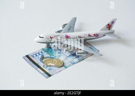 Avion jet avec kazakhstan monnaie nationale kzt tenge sur le arrière-plan blanc Banque D'Images