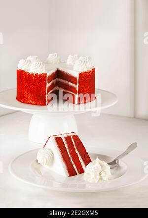 Gâteau de velours rouge isolé sur blanc avec une tranche de crème fouettée prêt à servir Banque D'Images