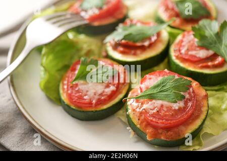 Des tranches de courgettes cuites au four sous forme d'en-cas végétarien avec garniture de tomates, de parmesan et de persil sur une assiette de laitue, gros plan, sélection de produits et Banque D'Images