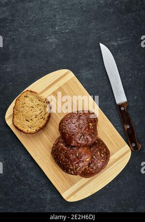 Petits pains de seigle avec graines de lin, de citrouille et de tournesol sur une planche en bois, vue du dessus Banque D'Images