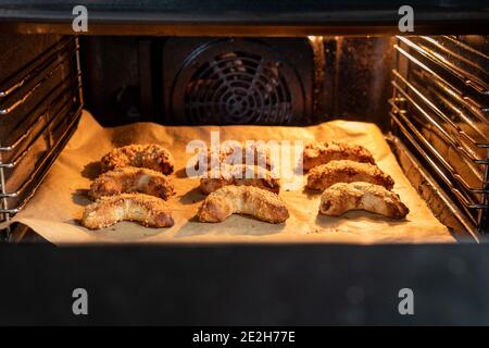 De délicieux croissants d'amande végétalienne fraîchement cuits avec des amandes hachées sur une plaque de cuisson dans un four éclairé. C'est une savoureuse pâtisserie macaron avec du massepain. Banque D'Images