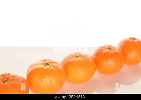 Plusieurs mandarines juteuses entières, mûres d'orange vif, situées en diagonale, sur un fond blanc. Le mandarin moyen, au cœur de l'action. Banque D'Images