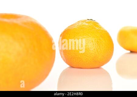 Trois mandarines entières, mûres d'orange juteuse et douces, situées en diagonale sur un fond blanc. Le Mandarin moyen au cœur de l'action. Banque D'Images