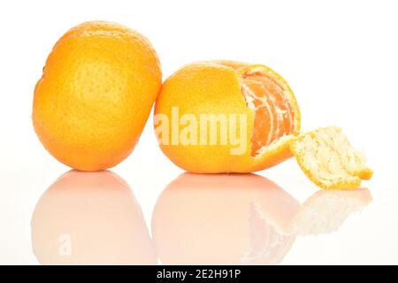 Deux mandarines douces et aigres entières, mûres d'orange vif, d'un côté de la mandarine, la croûte est à moitié débarrassée. L'arrière-plan est blanc. Banque D'Images