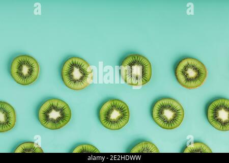 Les motifs des tranches de kiwi sur fond vert comme fond continu. Fond de fruit conceptuel texturé Banque D'Images