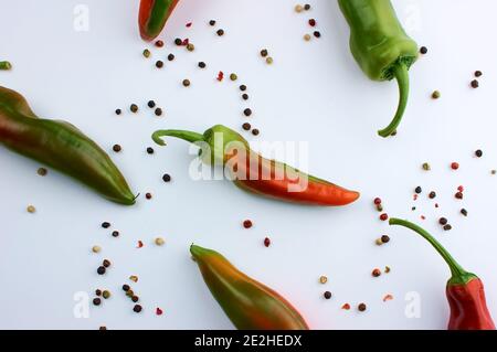 Haricots d'épices. Grains de poivre de couleur. Assaisonnement. Une gousse de poivre rouge chaud non mûr. Sur fond blanc. Banque D'Images