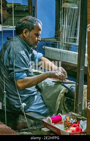 Varanasi, Uttar Pradesh, Inde - UN homme tissage de la soie à la main sur un vieux métier à tisser alimenté par les pieds. Le tissage de la soie est aacturing industrie dans Varanasi qui Banque D'Images