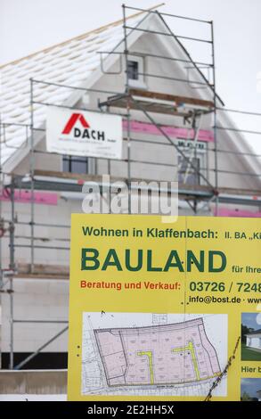 14 janvier 2021, Saxe, Klaffenbach : panneau publicitaire pour la construction de terrains devant un chantier de construction d'une nouvelle maison dans un développement enneigé. Photo: Jan Woitas/dpa-Zentralbild/ZB Banque D'Images