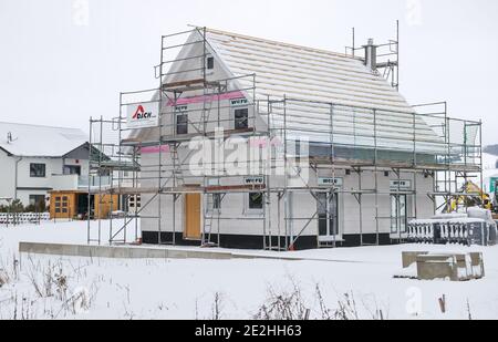 14 janvier 2021, Saxe, Klaffenbach : panneau publicitaire pour la construction de terrains devant un chantier de construction d'une nouvelle maison dans un développement enneigé. Photo: Jan Woitas/dpa-Zentralbild/ZB Banque D'Images