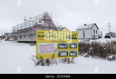 14 janvier 2021, Saxe, Klaffenbach : panneau publicitaire pour la construction de terrains devant un chantier de construction d'une nouvelle maison dans un développement enneigé. Photo: Jan Woitas/dpa-Zentralbild/ZB Banque D'Images