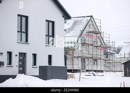 14 janvier 2021, Saxe, Klaffenbach : panneau publicitaire pour la construction de terrains devant un chantier de construction d'une nouvelle maison dans un développement enneigé. Photo: Jan Woitas/dpa-Zentralbild/ZB Banque D'Images