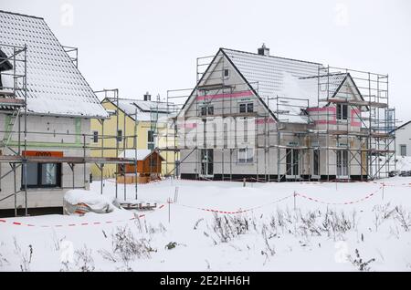 14 janvier 2021, Saxe, Klaffenbach : panneau publicitaire pour la construction de terrains devant un chantier de construction d'une nouvelle maison dans un développement enneigé. Photo: Jan Woitas/dpa-Zentralbild/ZB Banque D'Images